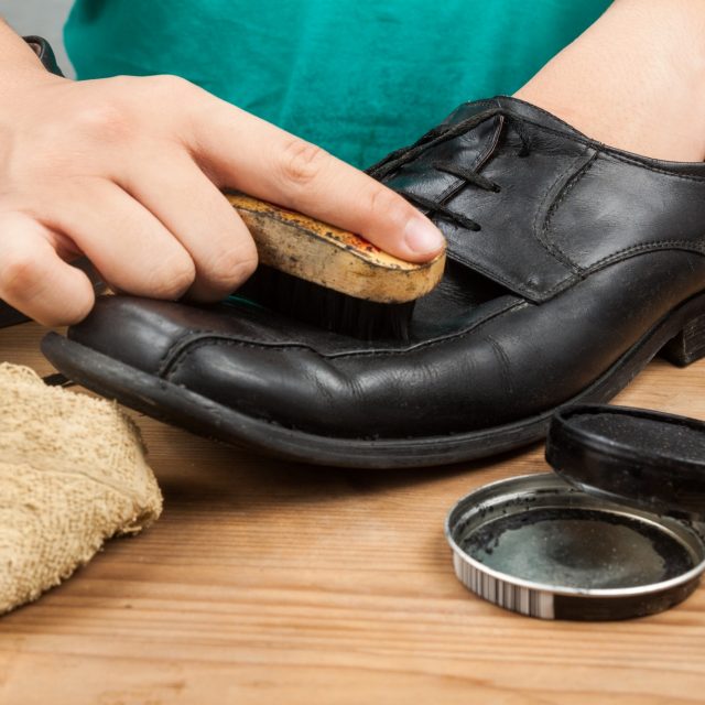 Person polishing and restoring worn out men’s formal shoes