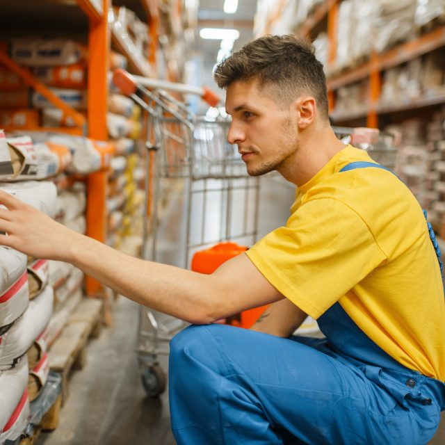 Male constructor choosing cement in hardware store